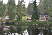 Står ved brua, snur meg og tar bilde av hyttene og bilene våres. Der ligger dem og sover enda, tenk på det
