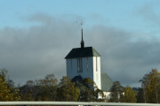 Ved Ullensaker Kirke ser vi en stor fugl ved spiret