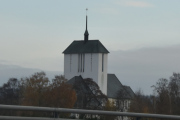 Vi passerer Ullensaker Kirke som også blir omtalt som Romeriksdomen, og er en langkirke fra 1958. Kirken er bygd i betong og har 650 plasser