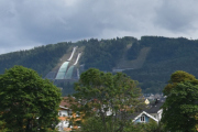 Der oppe ser vi Lysgårdsbakkene hoppanlegg i det fjerne - Olympiaparken. Du kan ta stolheis opp til toppen av den største bakken og nyte panoramautsikten ut over Lillehammer by og Norges største innsjø, Mjøsa. Hopptårnet er et populært fotostopp for alle tilreisende. Derfra kan du velge å ta de 936 trappetrinnene ned igjen, eller kjenne på den svevende følelsen i stolheisen...